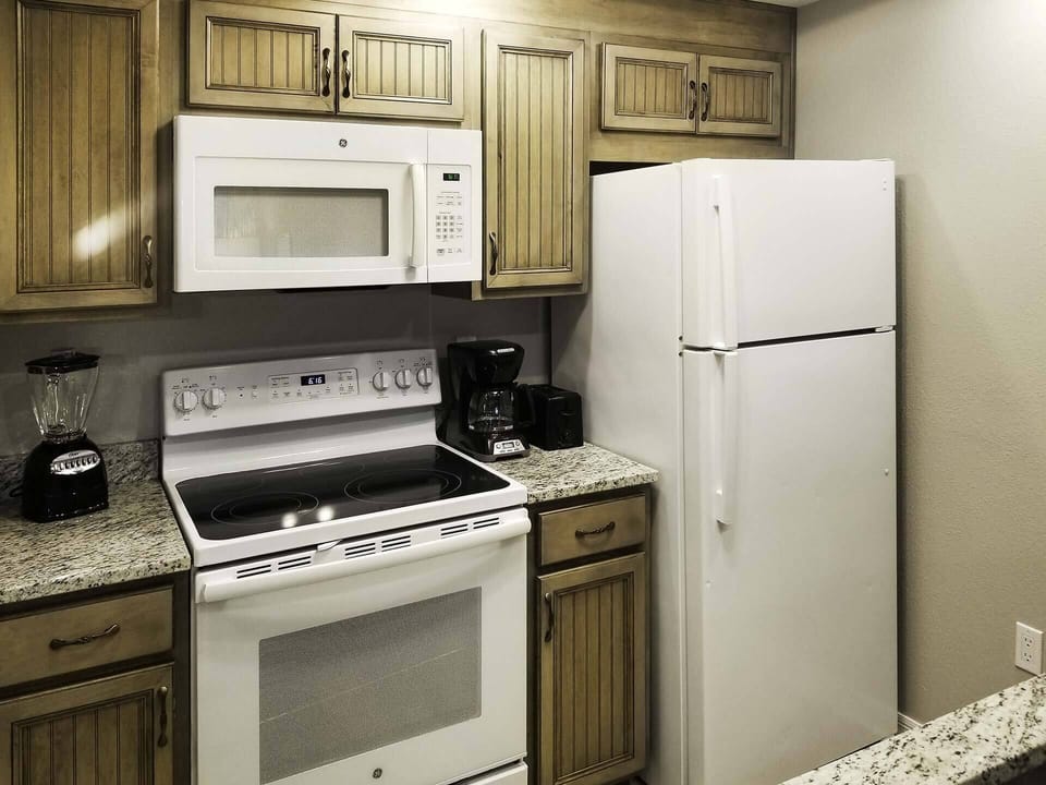Kitchen with refrigerator, stove, oven, blender, coffee maker, microwave & more.