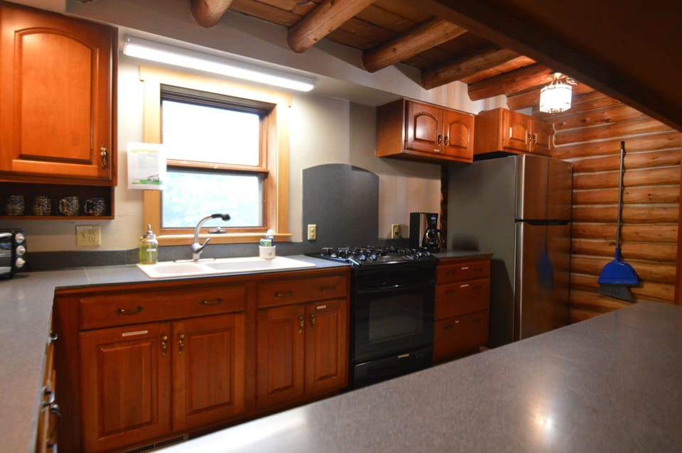 Kitchen with propane gas oven, full size refrigerator, and double bowl sink.