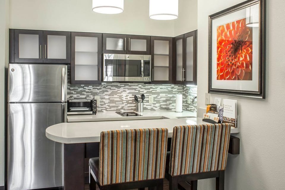 Enjoy cooking and dining in a sleek kitchen space featuring modern appliances and stylish bar seating for cozy meals.