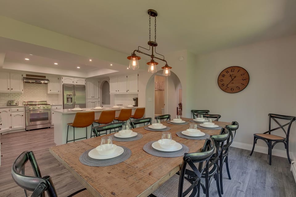 - Large dining table set for eight guests  
- Rustic wood design with farmhouse lighting  
- Connected to kitchen for family gatherings