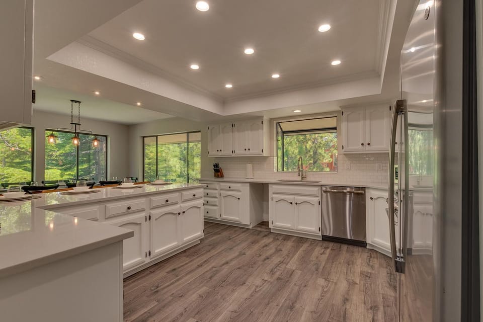 - Bright open kitchen with sleek white counters  
- Stainless steel appliances and forest views  
- Fully equipped for family cooking and dining