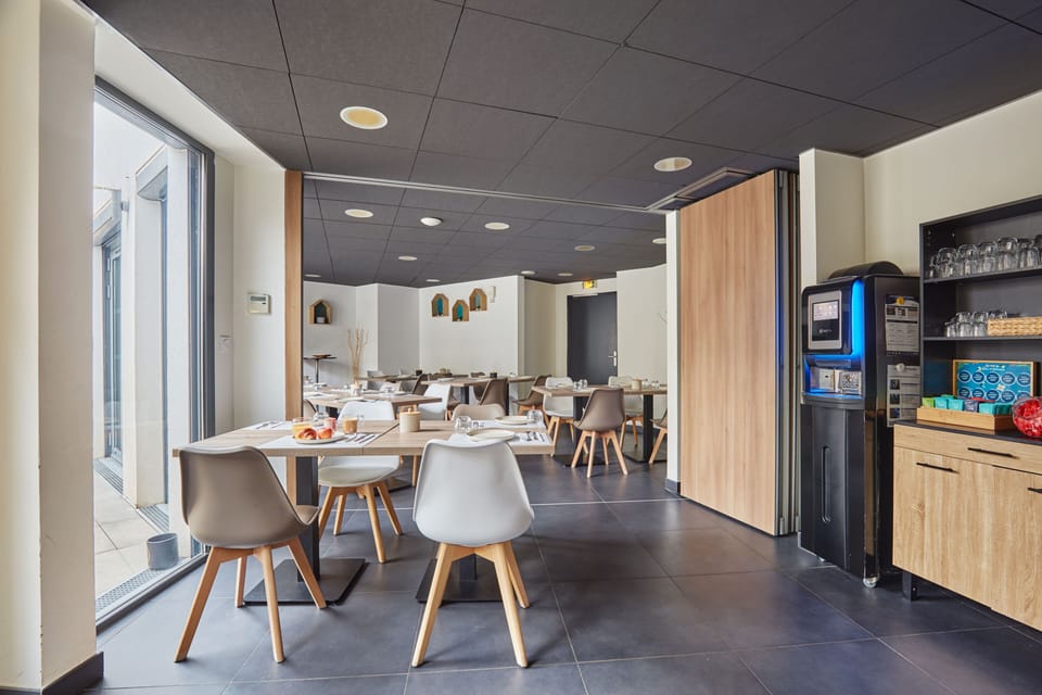 The chic dining area at Aparthotel Prado Castellane offers a modern ambiance with sleek furnishings, perfect for enjoying a leisurely breakfast while embracing the vibrant Marseille atmosphere.