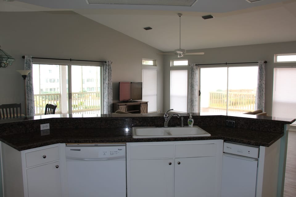 Living room, dining and kitchen with gulf and pool views