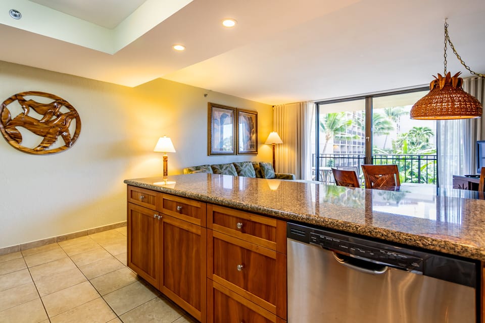 Cook comfortably in your island kitchen with granite counters and stainless appliances. Natural light streams through balcony doors, inviting you to enjoy tropical garden views while dining or unwinding.