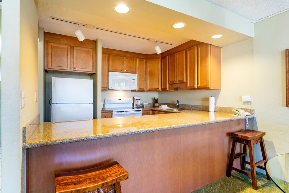 Prepare your favorite meals in this fully equipped kitchen with granite countertops, modern appliances, and a breakfast bar where you can gather for casual dining.