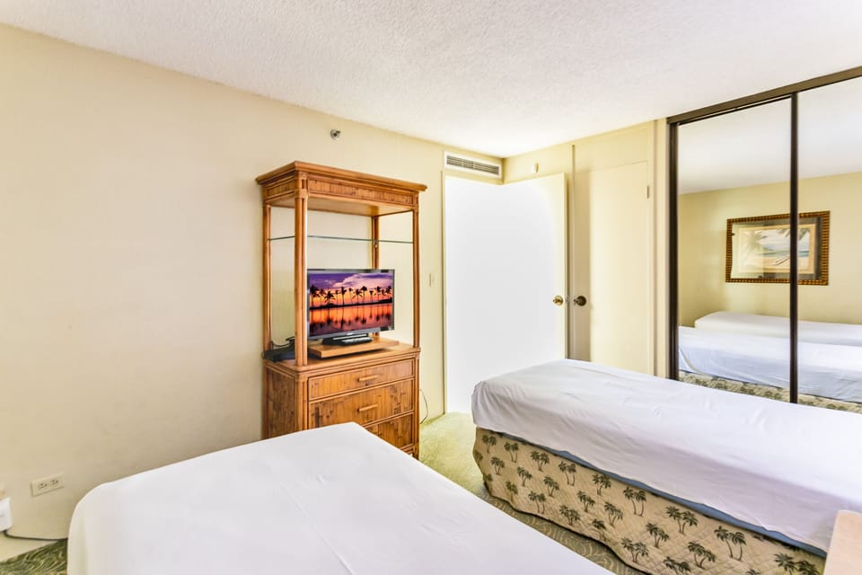 Unwind in your cozy bedroom with two comfortable beds, a mounted TV for evening entertainment, and mirrored closet doors that add a sense of space.