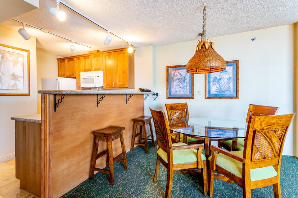 Picture yourself gathering around this inviting dining table with your loved ones after a day of adventure. The tropical-themed decor and open breakfast bar create a warm, relaxed atmosphere where your vacation memories will unfold.