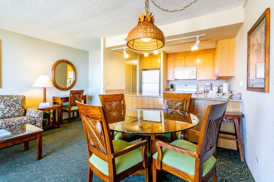 Relax in your island-inspired space with a welcoming living area flowing into a fully-equipped kitchen. The warm pendant lighting and tropical-carved dining chairs invite you to gather, cook, and unwind in effortless comfort.