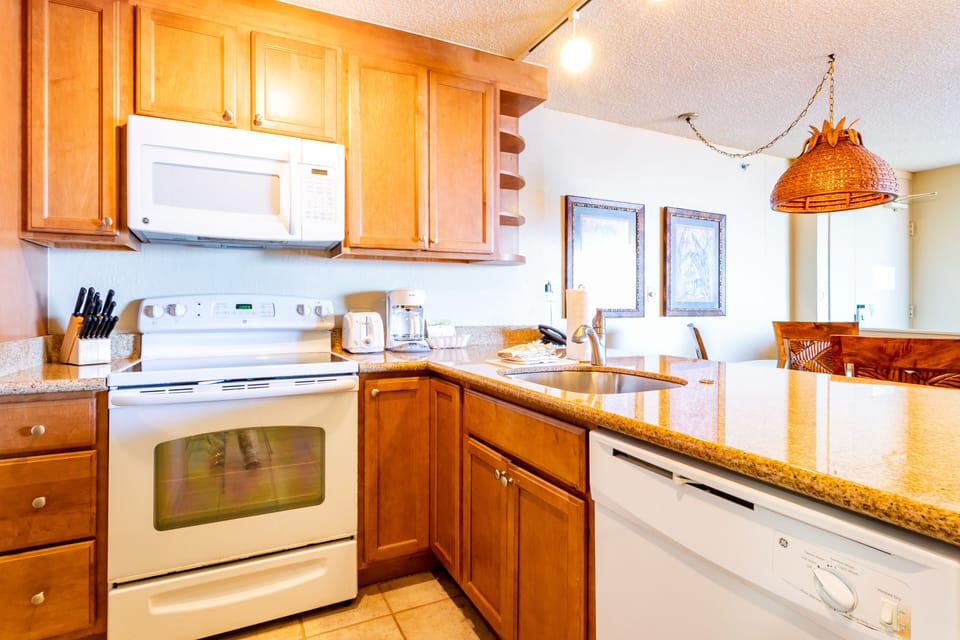 This fully equipped kitchen features warm wood cabinets, granite countertops, and modern appliances including a microwave, stove, and dishwasher—everything you need to prepare your favorite meals during your stay.