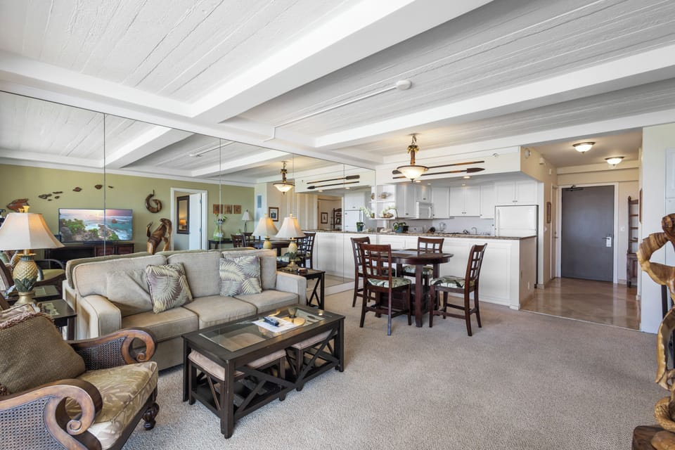 Step into your bright, open living space with vaulted ceilings and coastal décor. A comfy sofa awaits near your fully equipped kitchen and dining area—perfect for relaxing together.