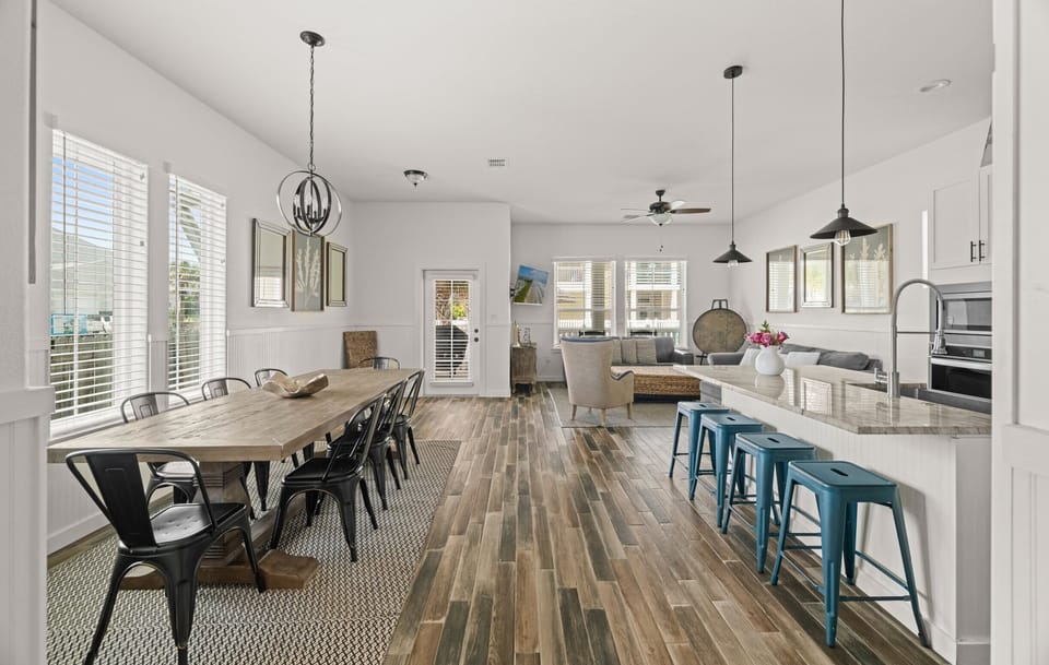 Open Floor Plan — Rustic Dining Table, Black Chairs, Orb Chandelier, Coral Art & Teal Stools