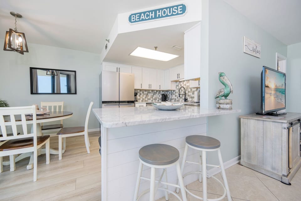 Bright kitchen with soft tile backsplash invites you to prepare fresh meals and chat at the breakfast bar