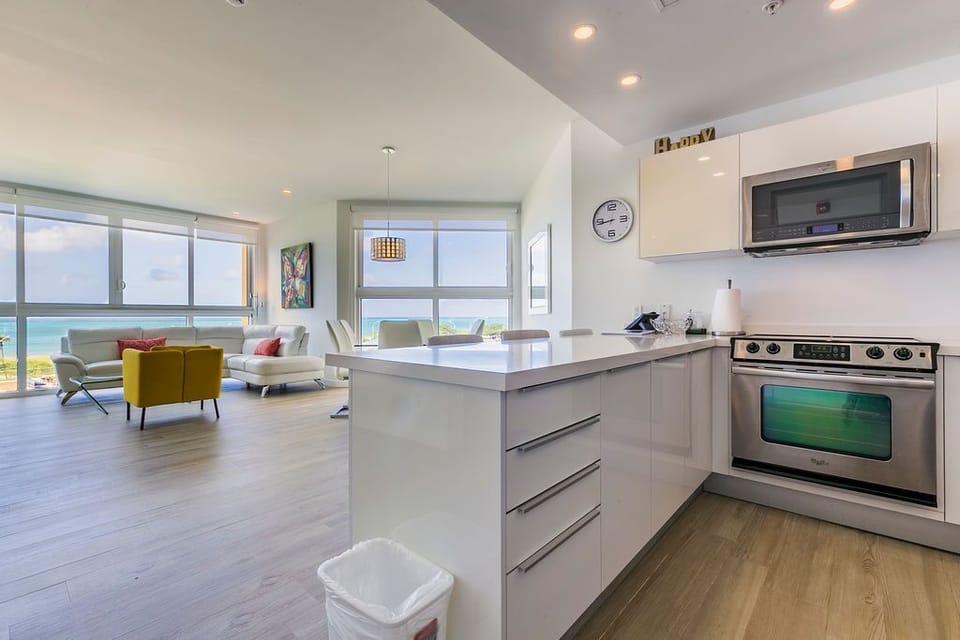 Your sleek, sun-filled retreat welcomes you with panoramic ocean views through floor-to-ceiling windows. Prepare meals in your modern kitchen while soaking in those turquoise blues, then relax in the airy living room where every moment feels like vacation.