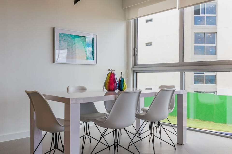 Gather around this stylish dining table with your travel companions and share stories from the day's adventures. The bright artwork and contemporary design create a welcoming space for memorable meals together.