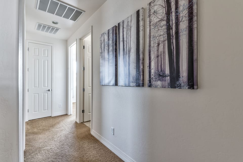 Upstairs hallway connects three bedrooms plus full bath and utility room