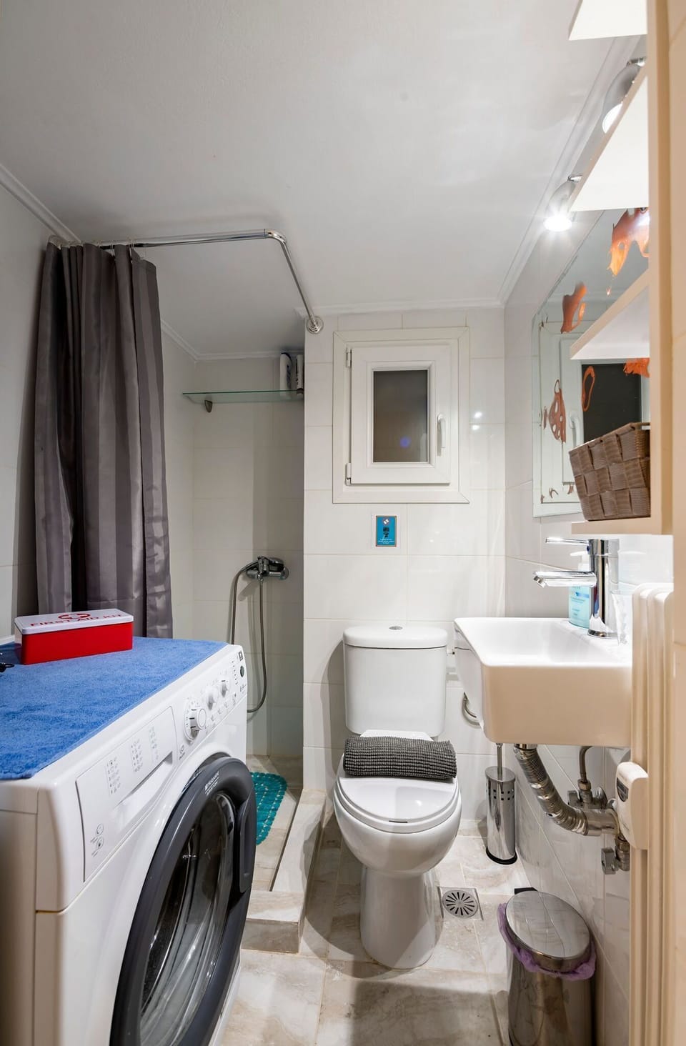 Small but practical bathroom equipped with washing machine.
