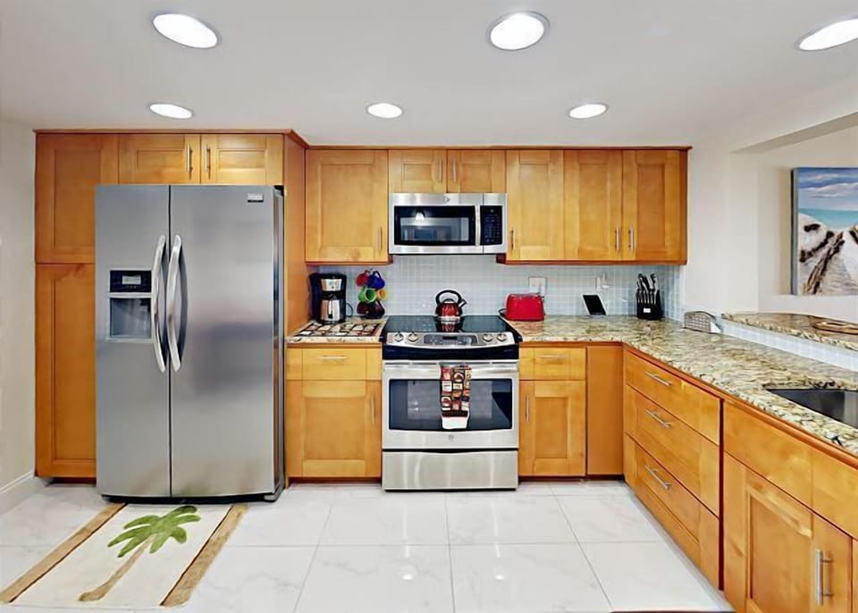 High end well stocked kitchen with stainless steel appliances and granite counters.