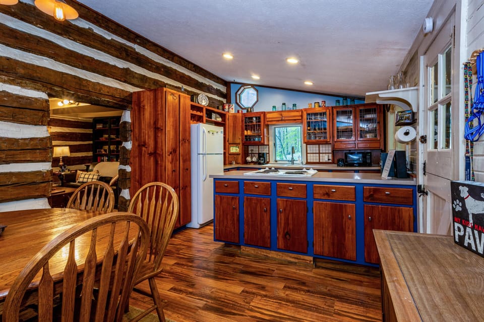 Cozy rustic kitchen with warm wood accents and an open dining area, perfect for gathering and shared meals.
