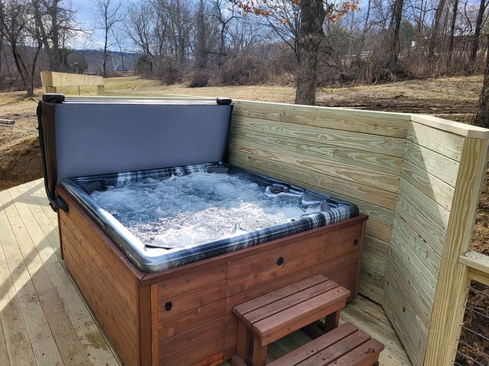 Outdoor hot tub with bubbling water, surrounded by new wood privacy walls and deck steps.
