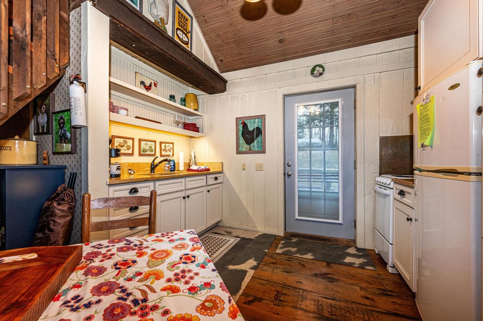 Kitchen area featuring white cabinetry, floral tablecloth, wood plank floors, and a glass-paneled back door.