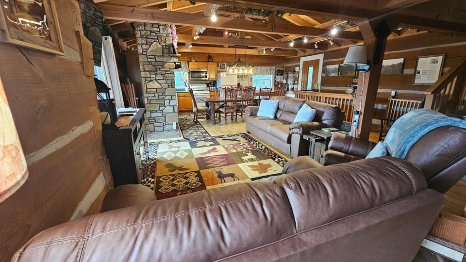 Leather sofas and armchair cluster around a patterned area rug in the open living and dining space.