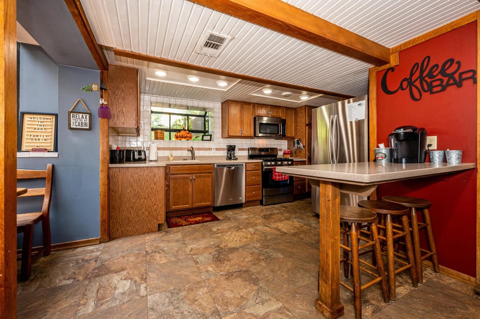 Kitchen features oak cabinets, stainless steel appliances, tiled backsplash, and a red accent wall with a coffee bar.