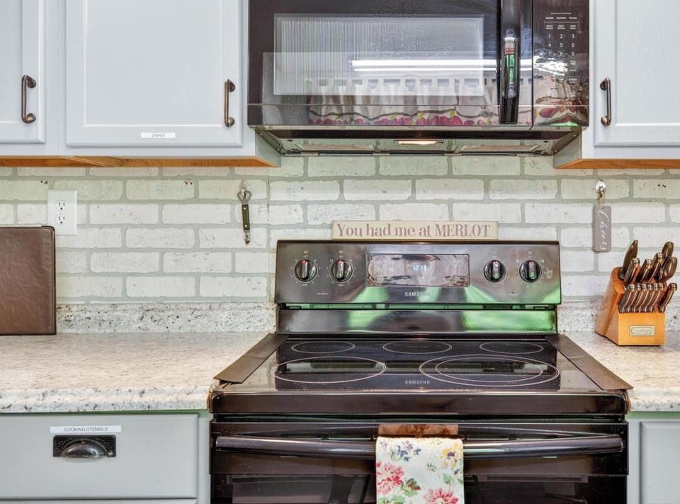 Electric stove and microwave are set against a whitewashed brick backsplash in the kitchen.