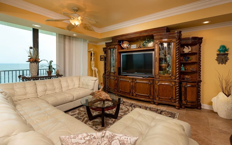 Relax in the spacious living area with a plush sectional, elegant decor, and a large TV for your entertainment