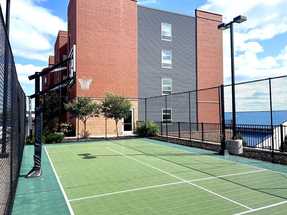 Outdoor basketball and sports court surrounded by green landscaping.