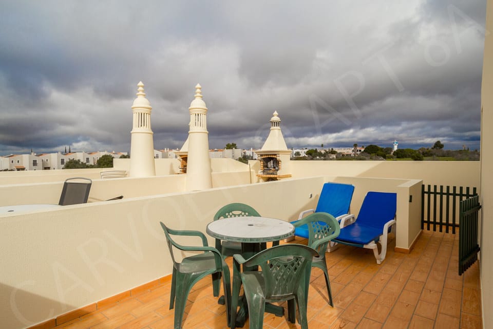 Rooftop terrace at Carvoeiro Apartment 8A with outdoor seating, traditional Algarve chimneys and panoramic views, a wonderful spot for relaxing in this 2-bedroom holiday apartment near Carvoeiro