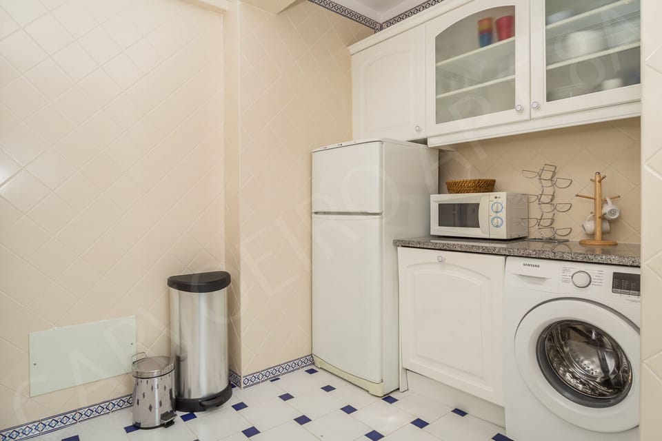 Kitchen at Carvoeiro Apartment 8A with microwave, blue and white tiled floor, and modern appliances for convenient self-catering in this 2-bedroom Algarve holiday apartment