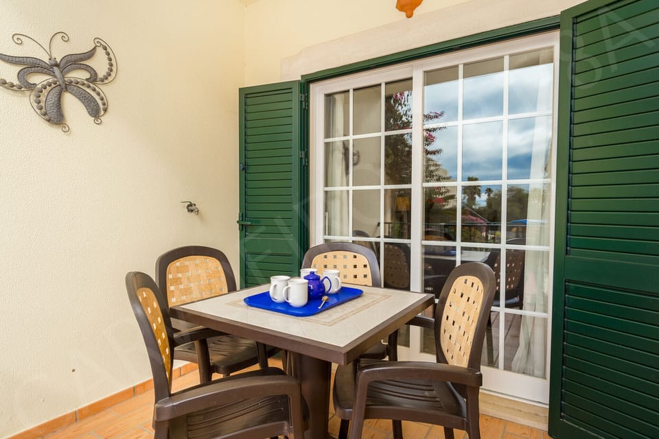 Covered terrace at Carvoeiro Apartment 8A with outdoor dining table and chairs, decorative wall art, ideal for al fresco dining in this 2-bedroom Algarve holiday apartment