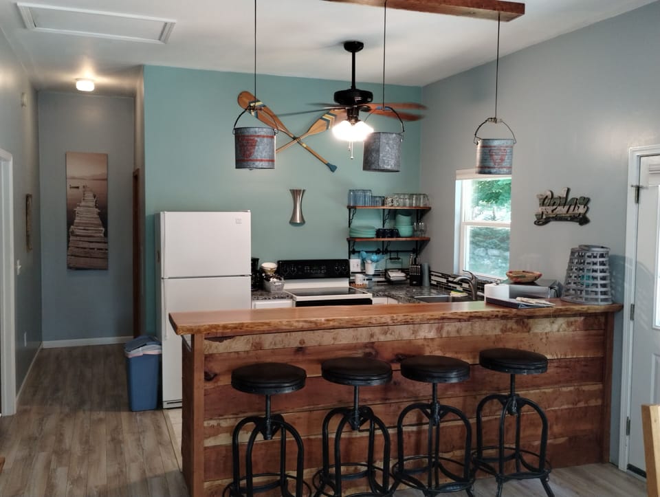 Beautiful kitchen with live-edge bar and reclaimed minnow bucket lights.
