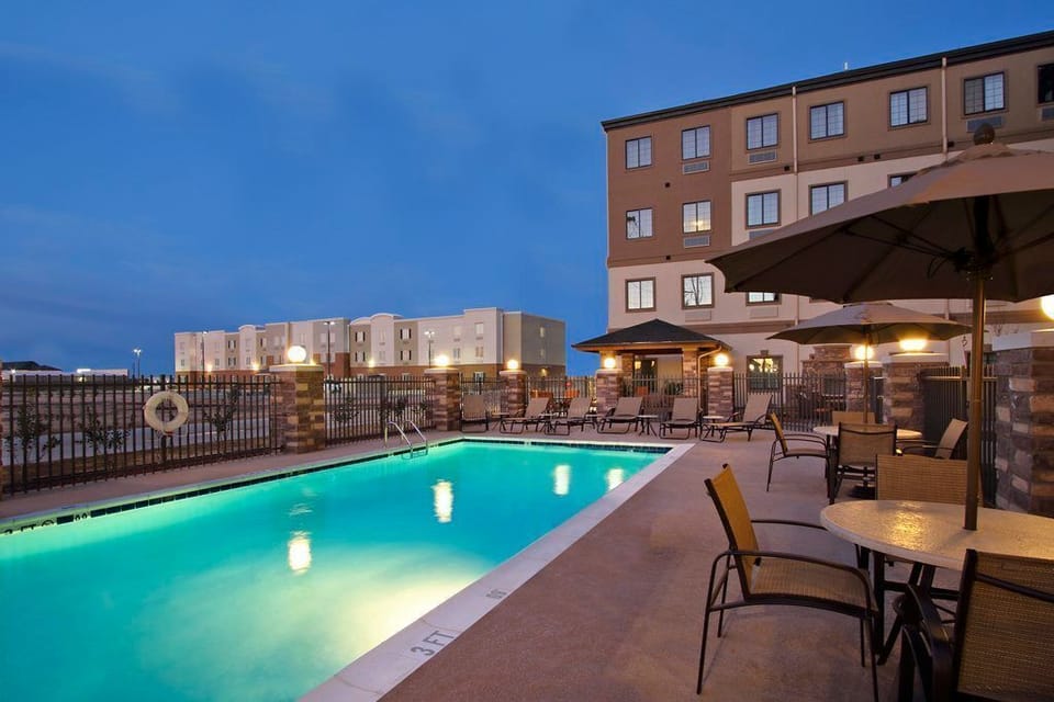 Outdoor pool with lounge seating and umbrellas at dusk.