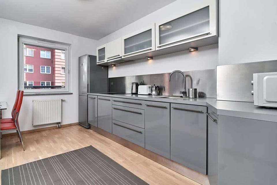 Another angle of the same kitchen seen earlier, highlighting the fridge and more counter space. The kitchen has a neutral, modern look with light colors.