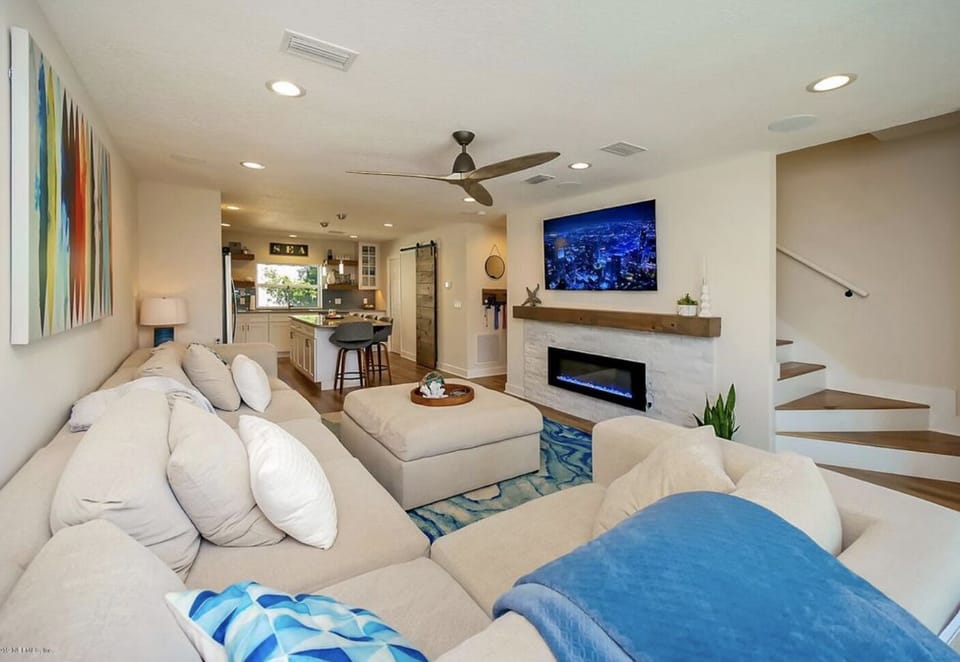 Living room features an oversized sofa and 72inch 4K TV
