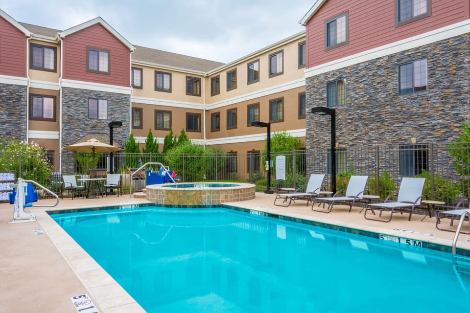 Outdoor pool with lounge chairs and surrounding greenery - open seasonally from 8 AM to 10 PM