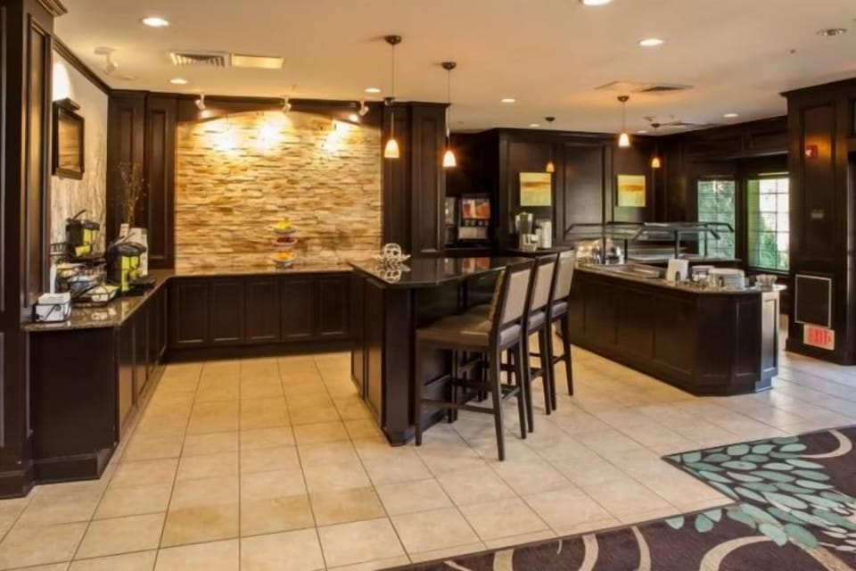 Breakfast service area with a wood-panelled coffee station, dispensers, and adjacent seating