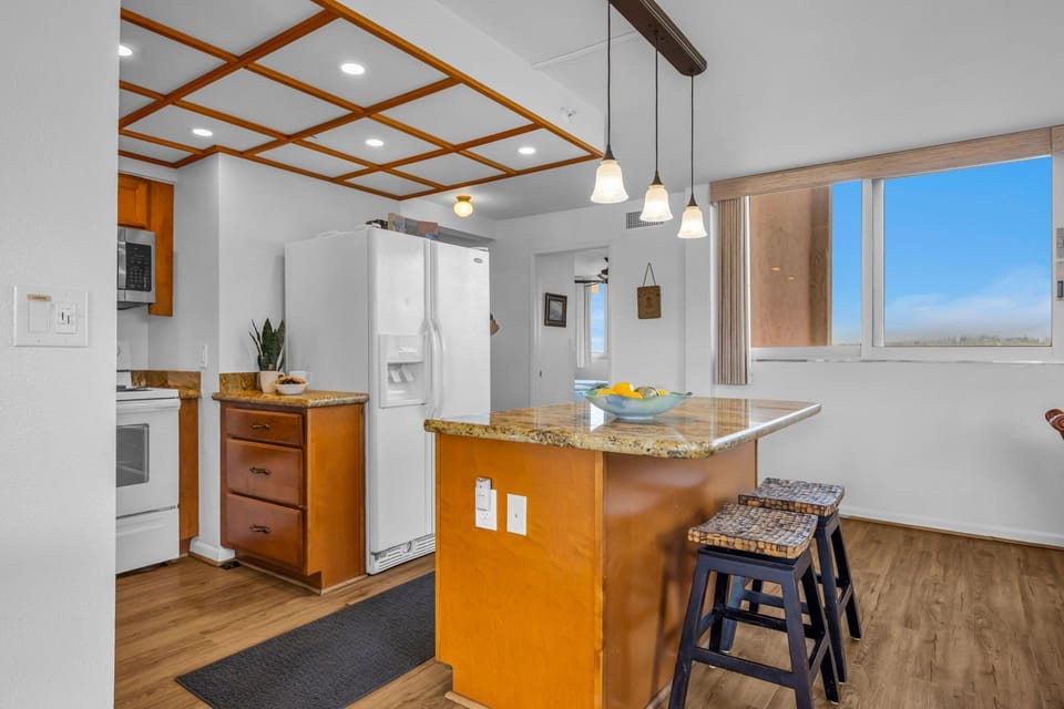 Wooden cabinetry, granite countertops, and a decorative ceiling grid give the kitchen both function and style.
