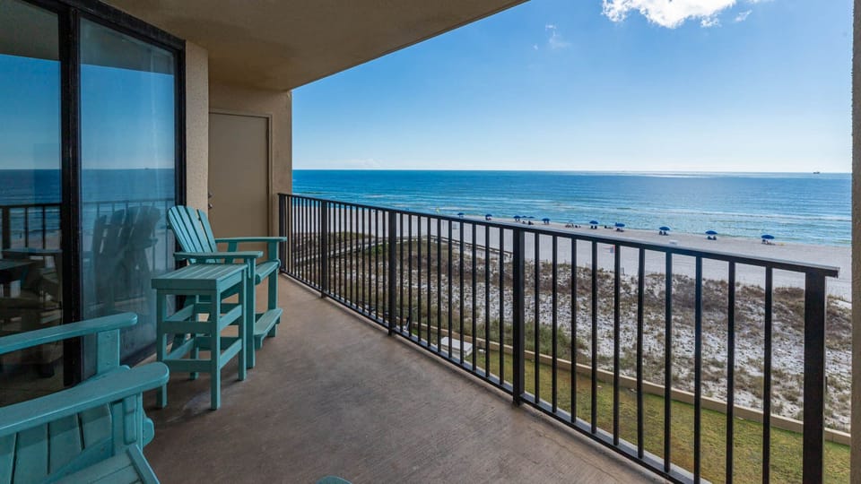 Relax on the turquoise chairs of the balcony, overlooking the tranquil beach and sparkling waters just steps away