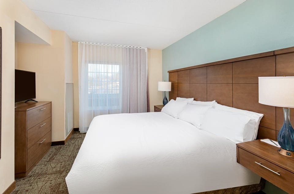 Spacious bedroom with a king bed, soft lighting, and modern furnishings.