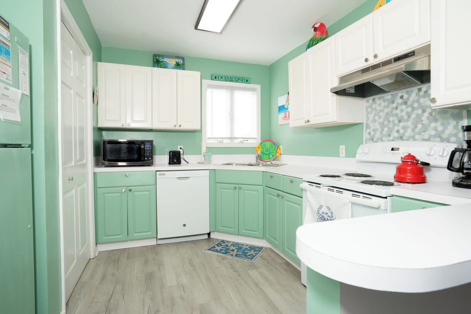 Your bright, tropical-themed kitchen awaits with cheerful mint cabinets and modern appliances for home-cooked meals.