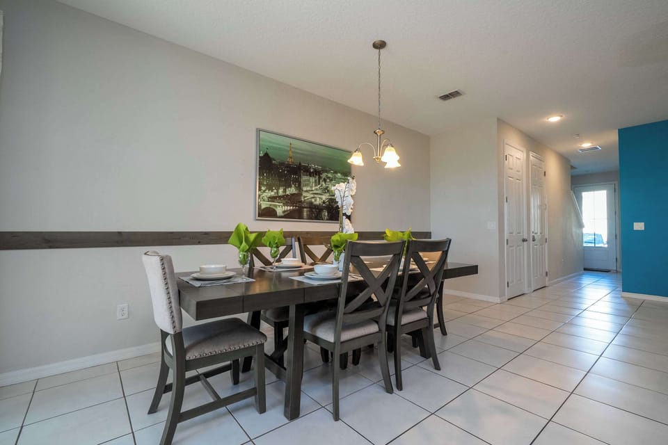 Roomy dining area with a contemporary table for eight and warm pendant lighting-perfect for family meals or board games.