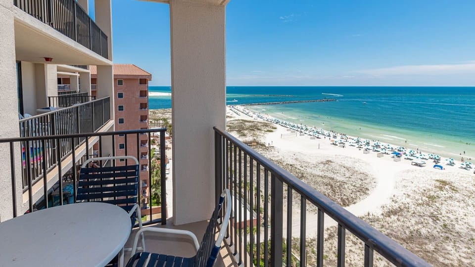Enjoy the view from your balcony, featuring seating and a stunning landscape of beach umbrellas and clear waters