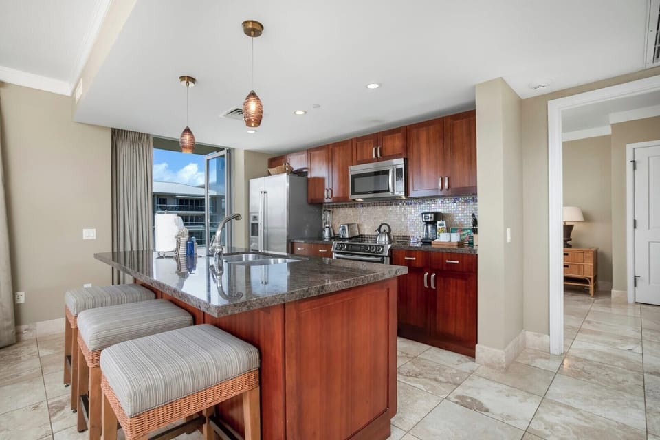 Bright gourmet kitchen with granite island, rich wood cabinets, coastal luxury.