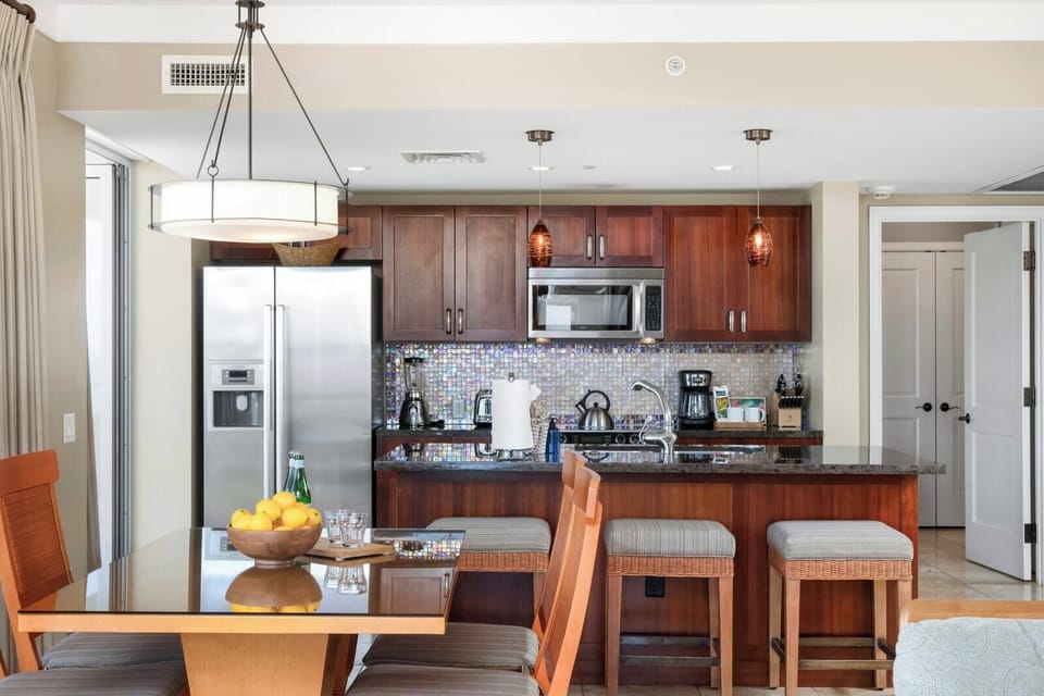 Modern kitchen with island seating, stainless appliances, and tropical elegance.