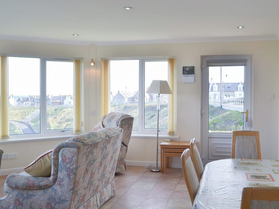 Sun room with dining area and dramatic views over the town | White Gables - Scott Holiday Cottages, Portknockie