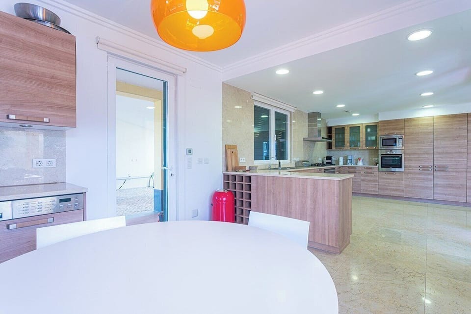 Modern open-plan kitchen with wood cabinetry and orange pendant light — Villa Belga Queen, holiday villa in Cascais