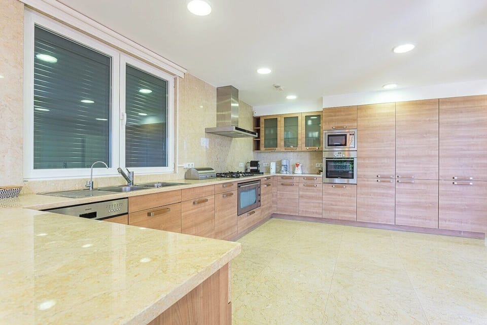 Modern kitchen with light stone countertops and wooden cabinetry — Villa Belga Queen, luxury holiday villa in Cascais
