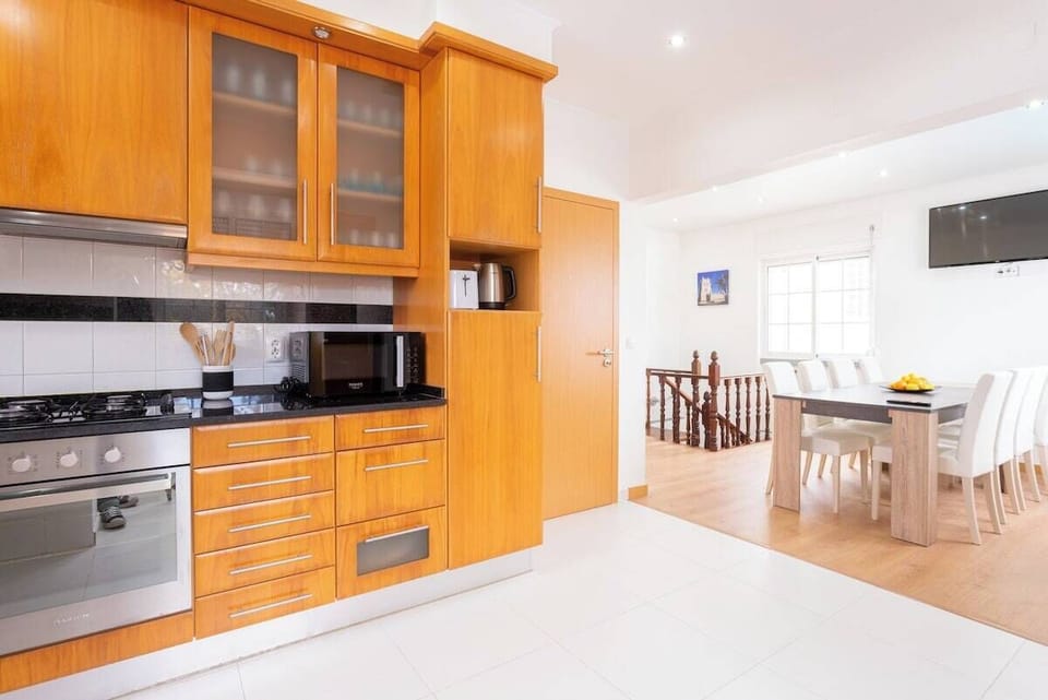 Modern open-plan kitchen with wooden cabinetry and dining area — Villa Sol e Mar, holiday villa in Charneca da Caparica